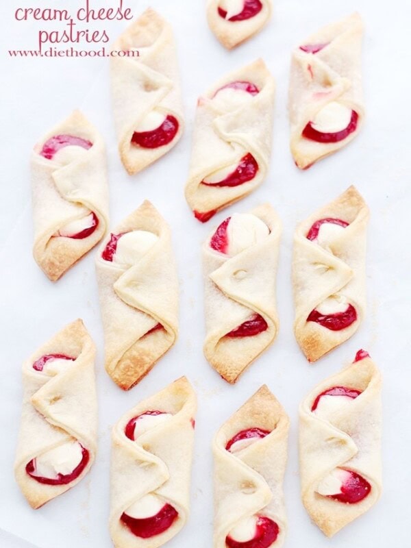 Several pastries filled with strawberry jam and soft sweetened cream cheese are arranged on a white background.
