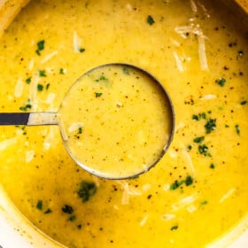 A ladle full of broccoli potato soup held over a pot.