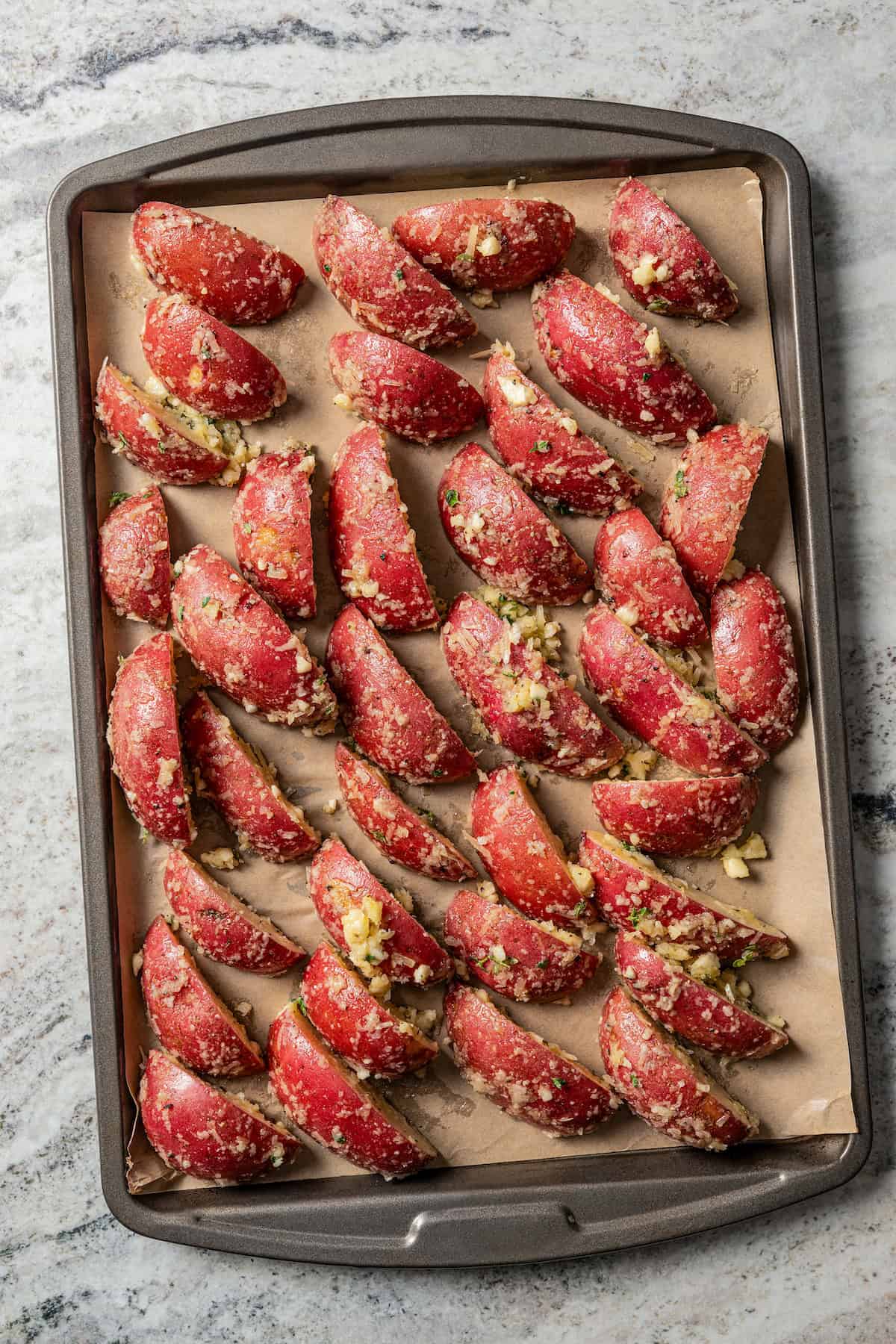 Overhead view of seasoned potatoes on a baking sheet.