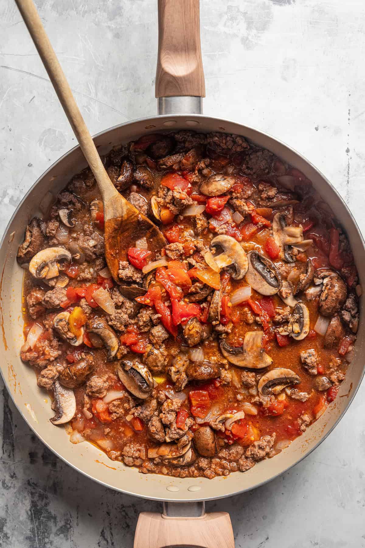 Ground beef and mushrooms with tomato sauce in a skillet.