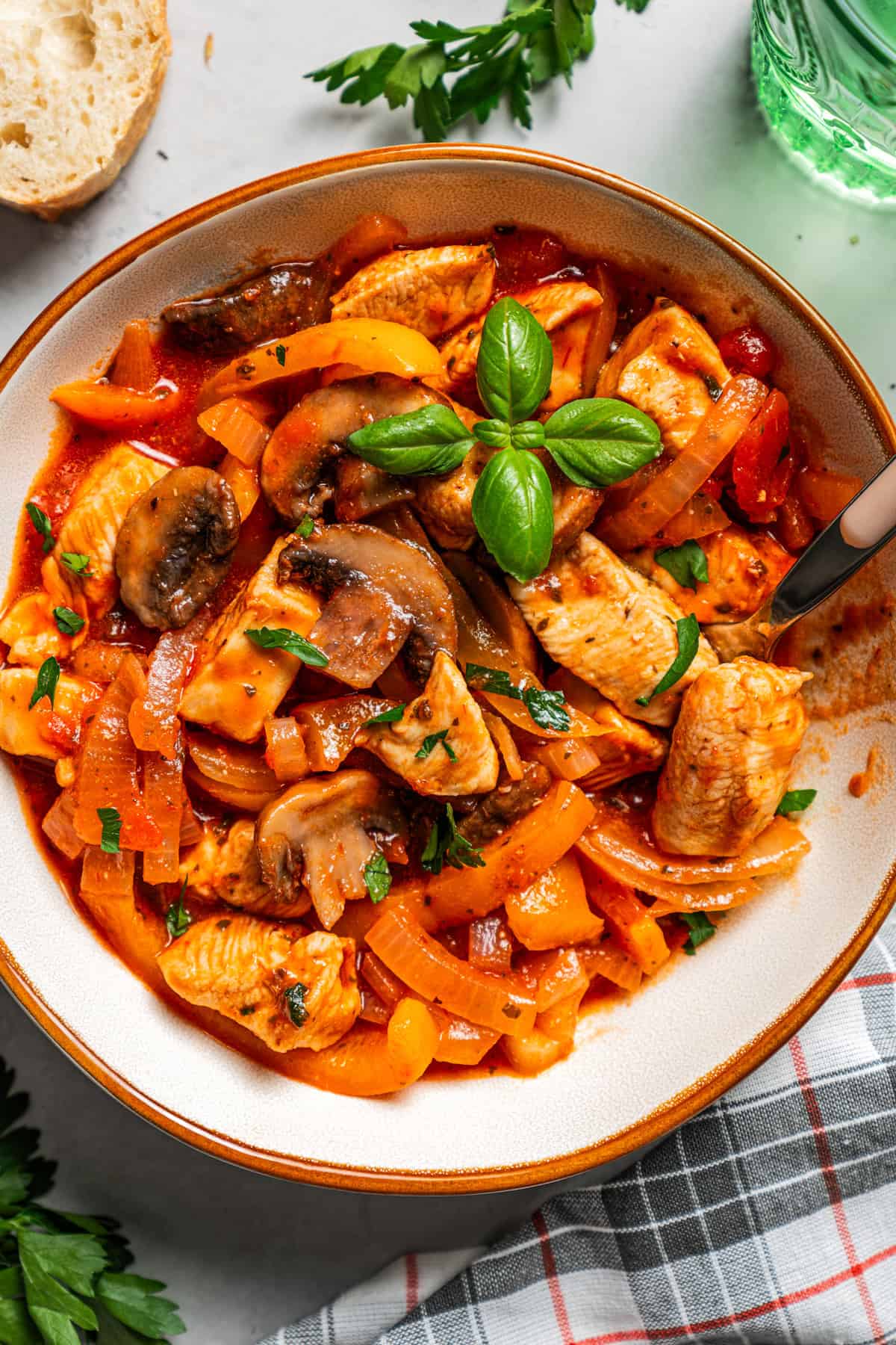 Overhead image of a bowl with chicken, mushrooms, onions, and bell peppers in tomato sauce.