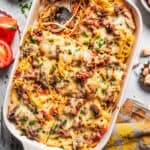 Overhead view of a baked spaghetti casserole in a baking dish, with a serving missing from the corner.