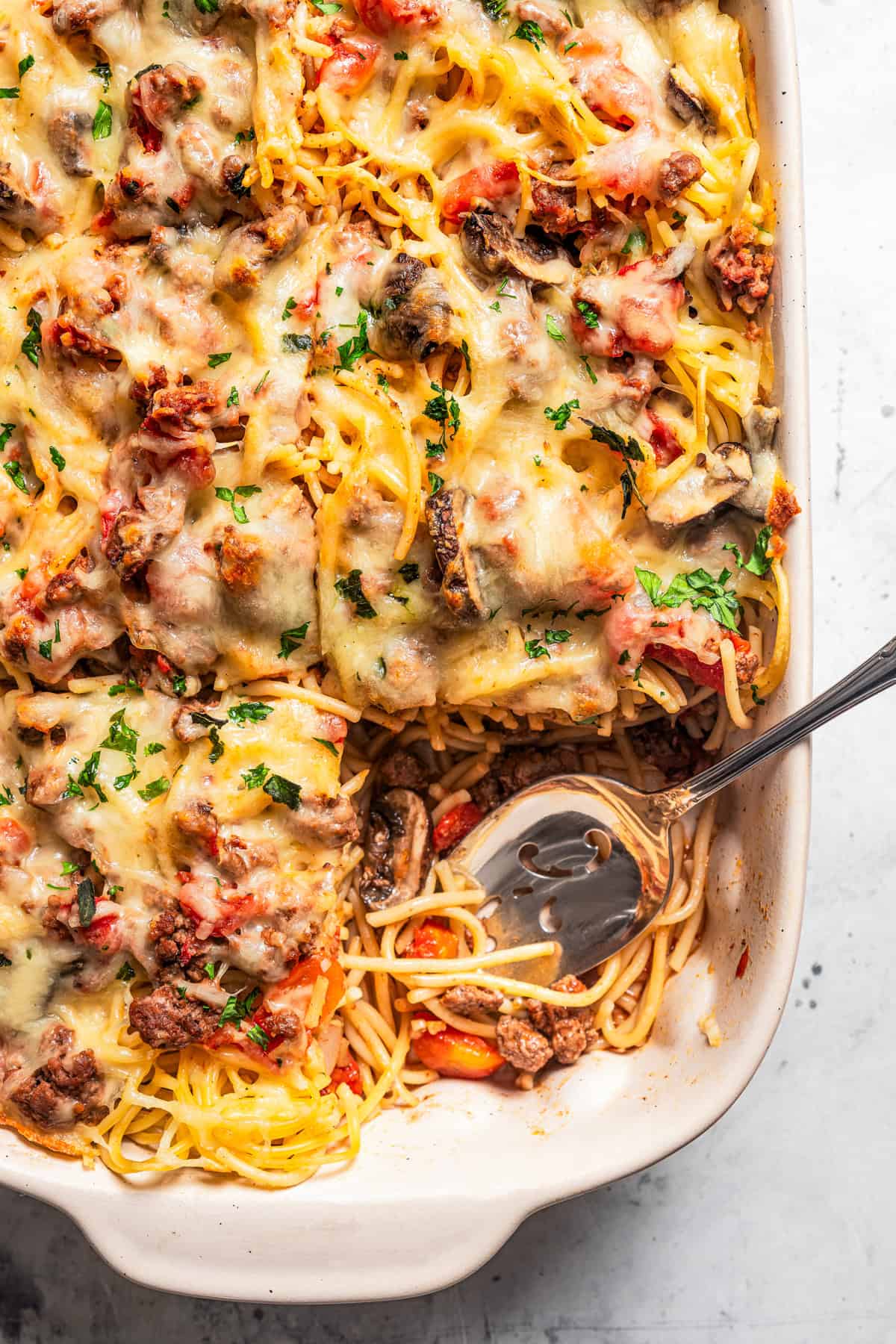 Pasta casserole in a baking dish, with a serving missing from the corner.