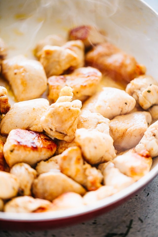Cooking pieces of chicken in a skillet.