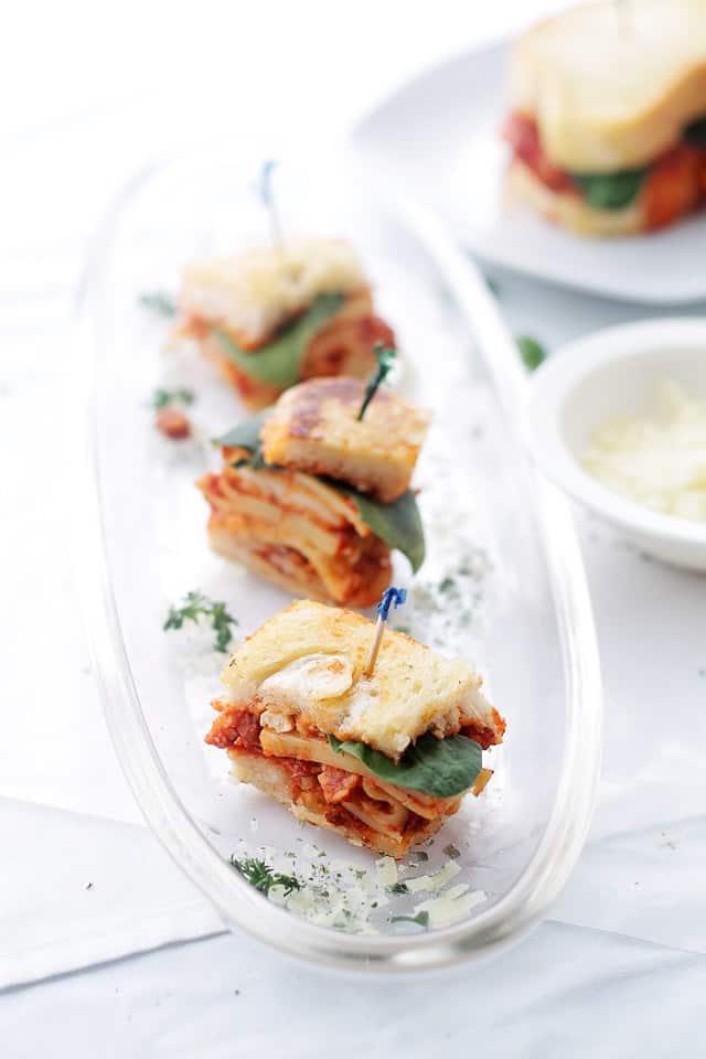 Grilled cheese made with lasagna cute into small appetizer bites on a clear tray