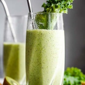 close up shot of two tall drinking glasses with green smoothie