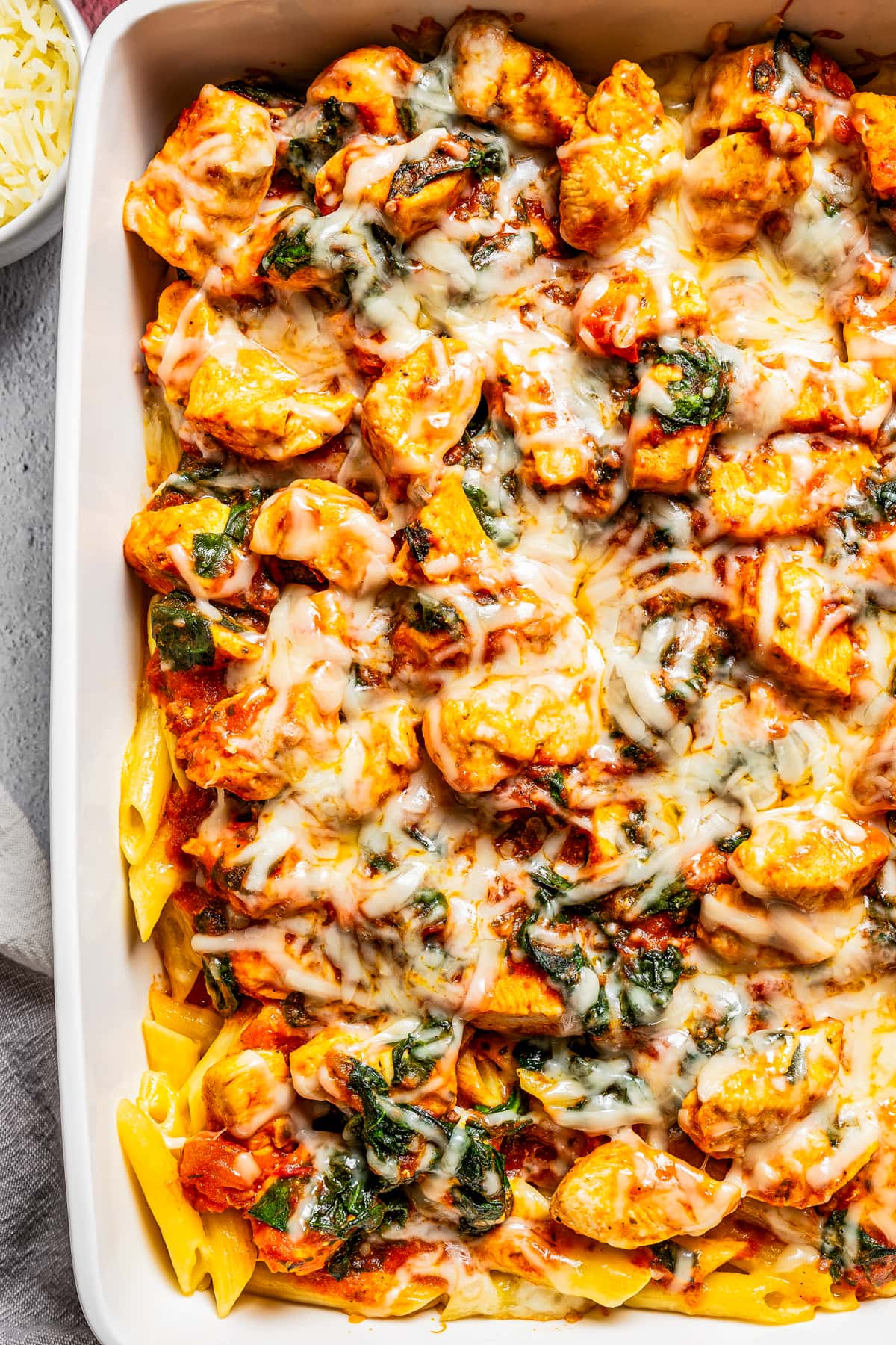 Close-up image of past and chicken in a casserole dish, topped with melted cheese.