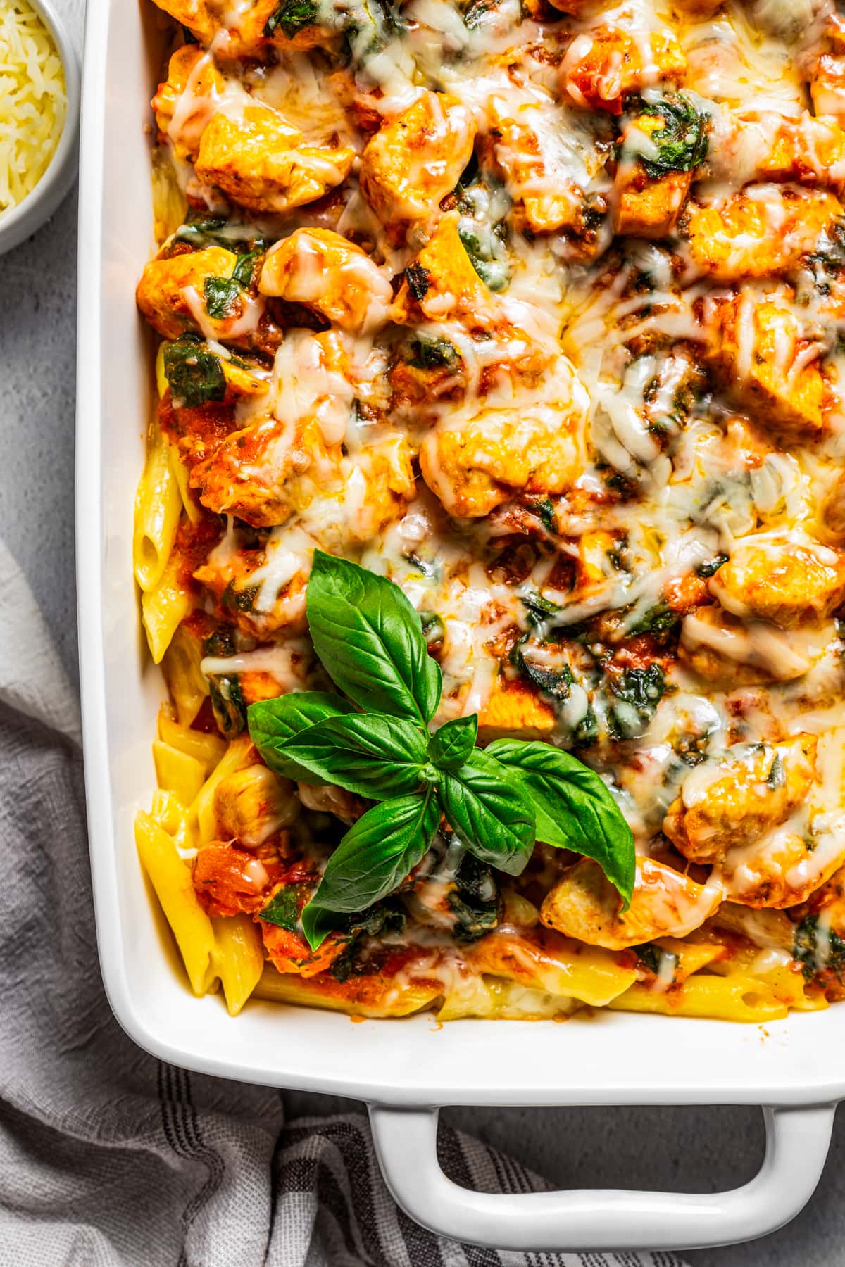 Overhead view of a pasta bake in a casserole dish garnished with basil leaves.