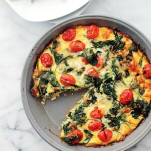 Overhead view of baked eggs with spinach and tomatoes.