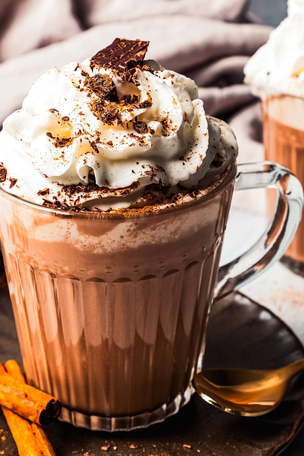 Up close photo of coffee served in a glass mug and topped with whipped cream and chocolate shavings.