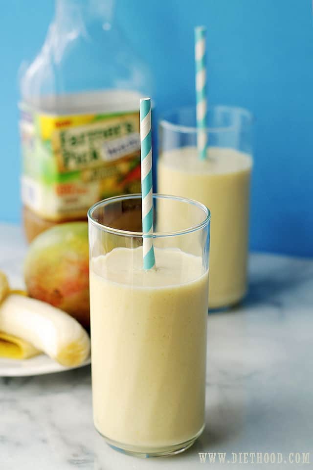 Two glasses of banana mango smoothies with straws.