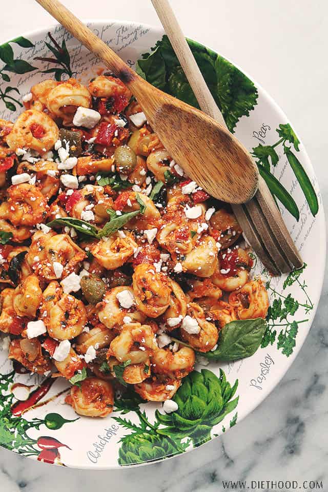 tortellini in a large bowl with salad spoons