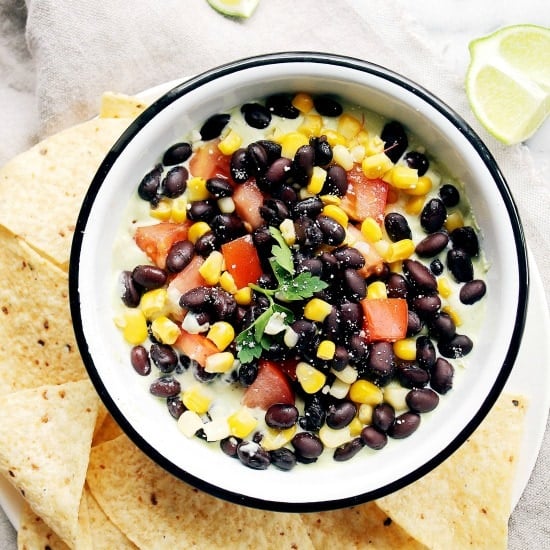 Southwestern Avocado Dip in a white bowl with a black rim and surrounded by chips