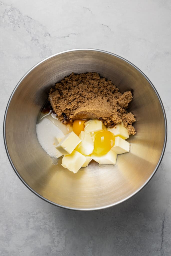 A mixing bowl with butter, sugar, brown sugar, and eggs in it