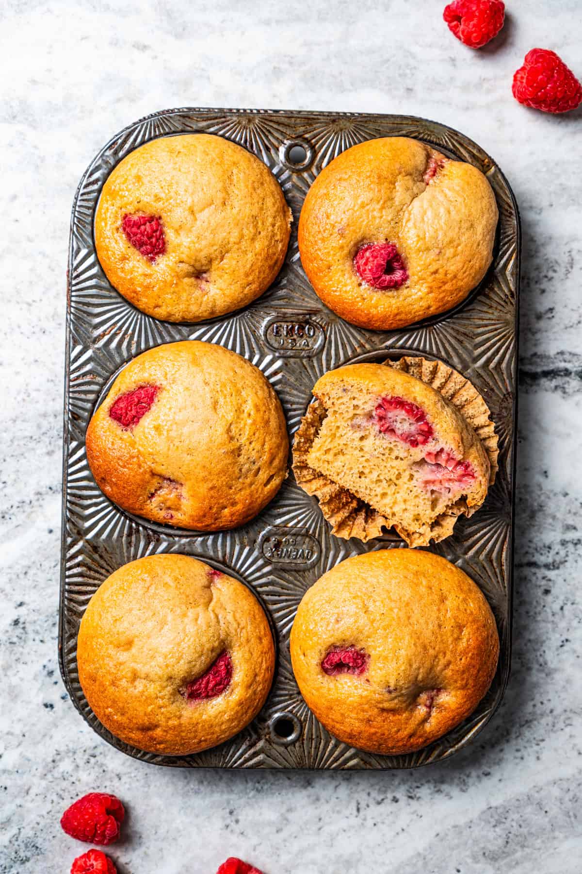 These easy raspberry muffins are fluffy and moist, made with yogurt, brown sugar, and heaps of fresh raspberries. Like summer in a muffin pan! Raspberry muffins in a muffin pan.