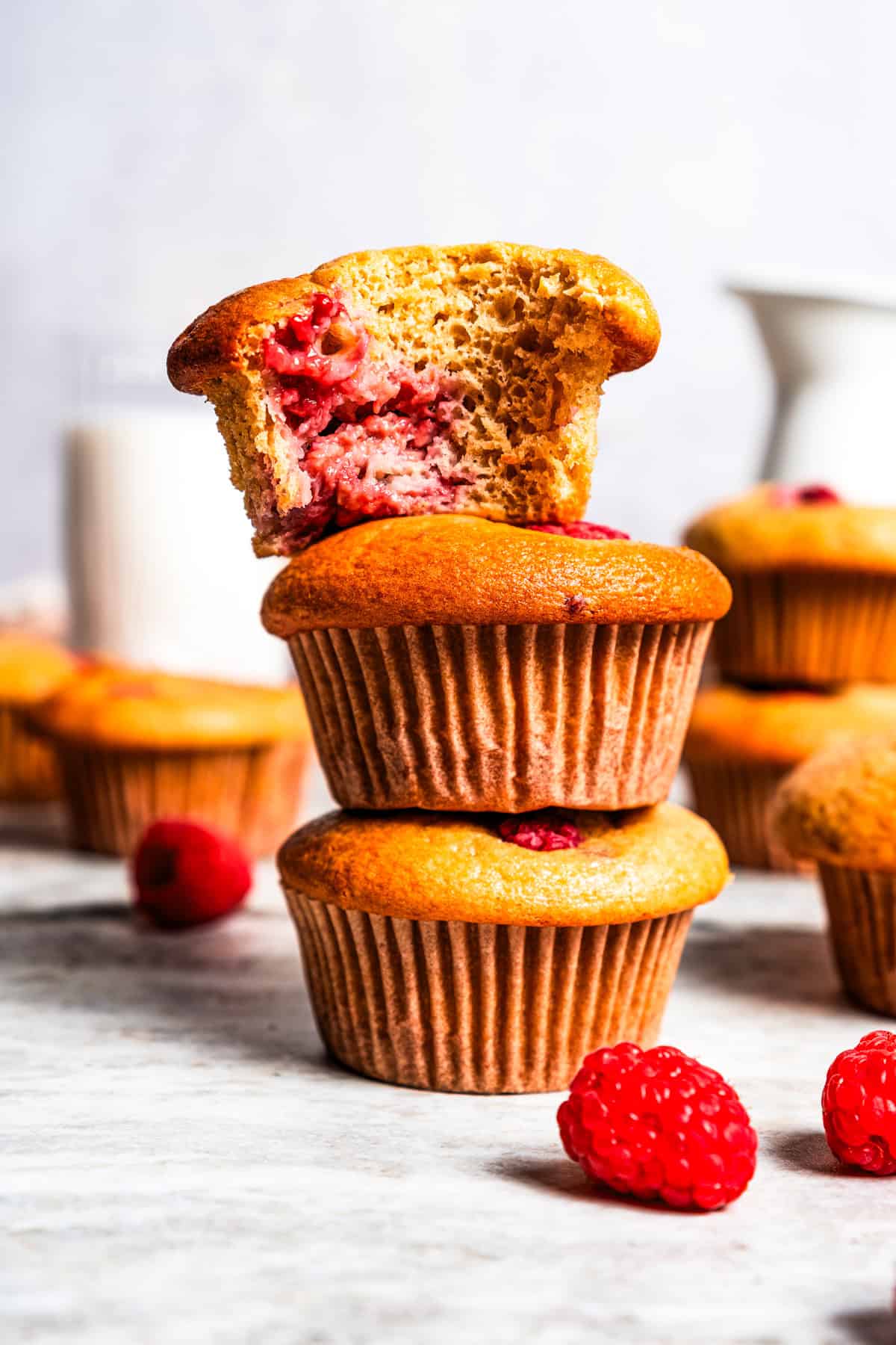 These easy raspberry muffins are fluffy and moist, made with yogurt, brown sugar, and heaps of fresh raspberries. Like summer in a muffin pan! Three muffins stacked.