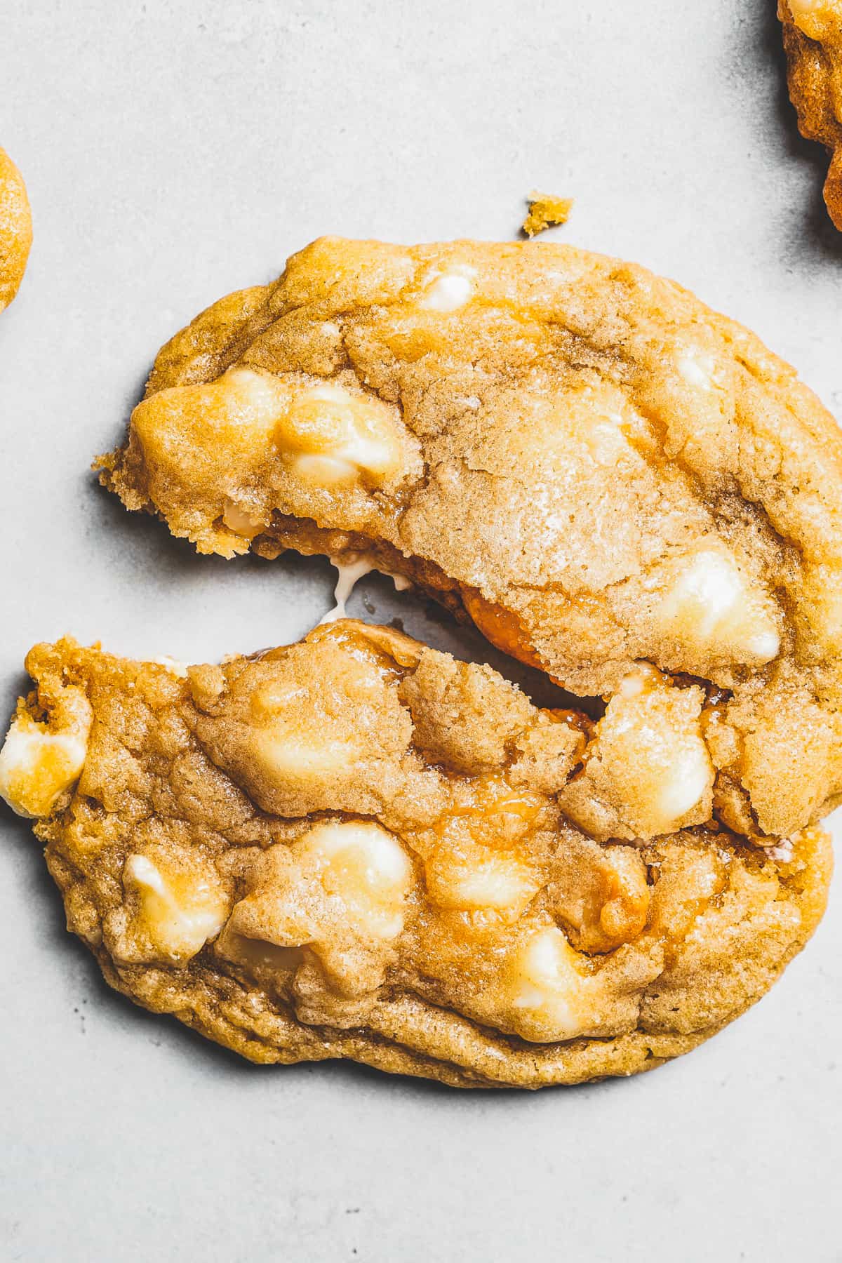 Overhead view of a white chocolate chip cookie split in half.