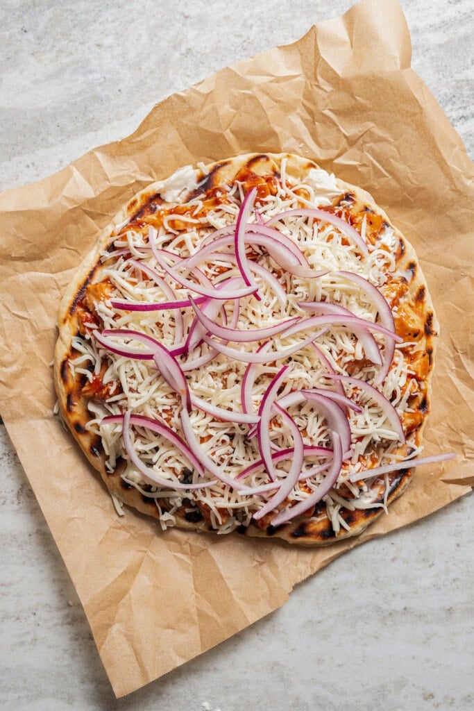 Red onions and cheese layered over BBQ chicken on a grilled pizza crust.