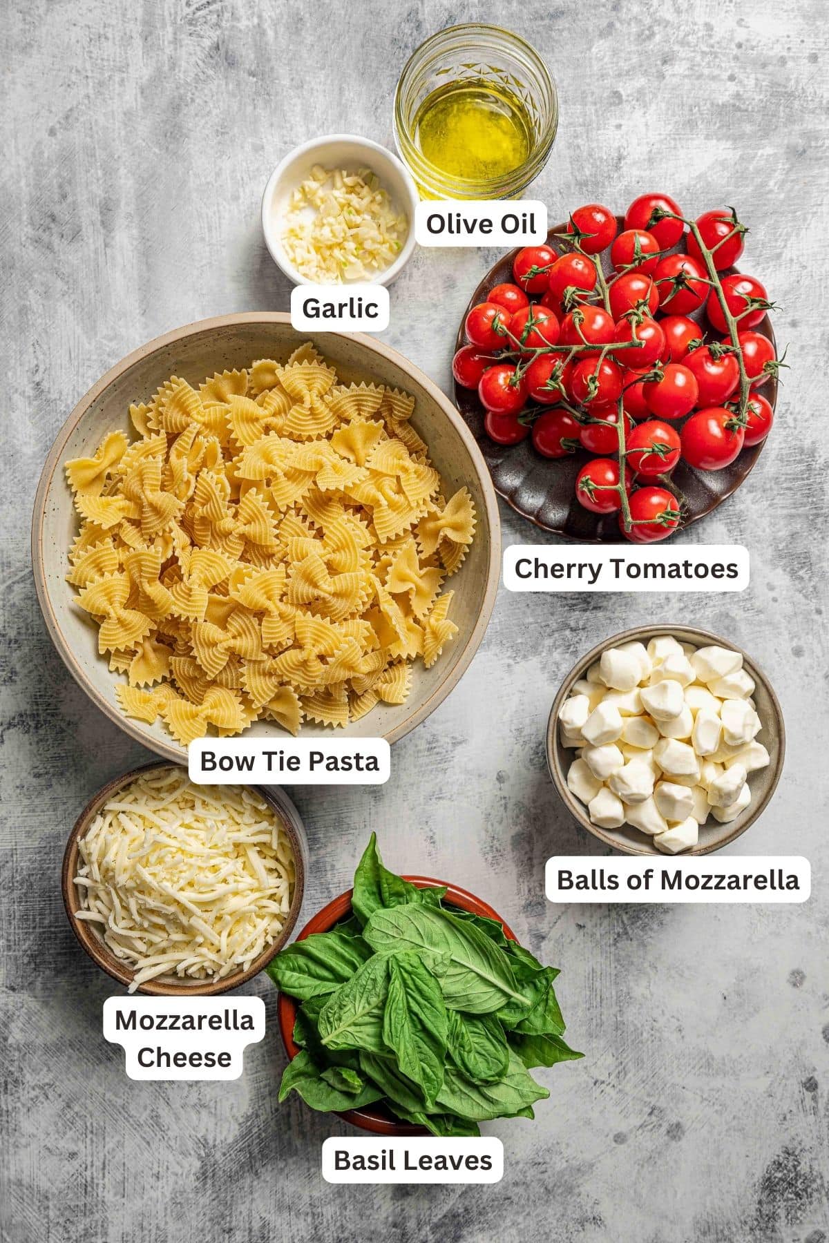Ingredients for caprese pasta with text labels overlaying each ingredient.