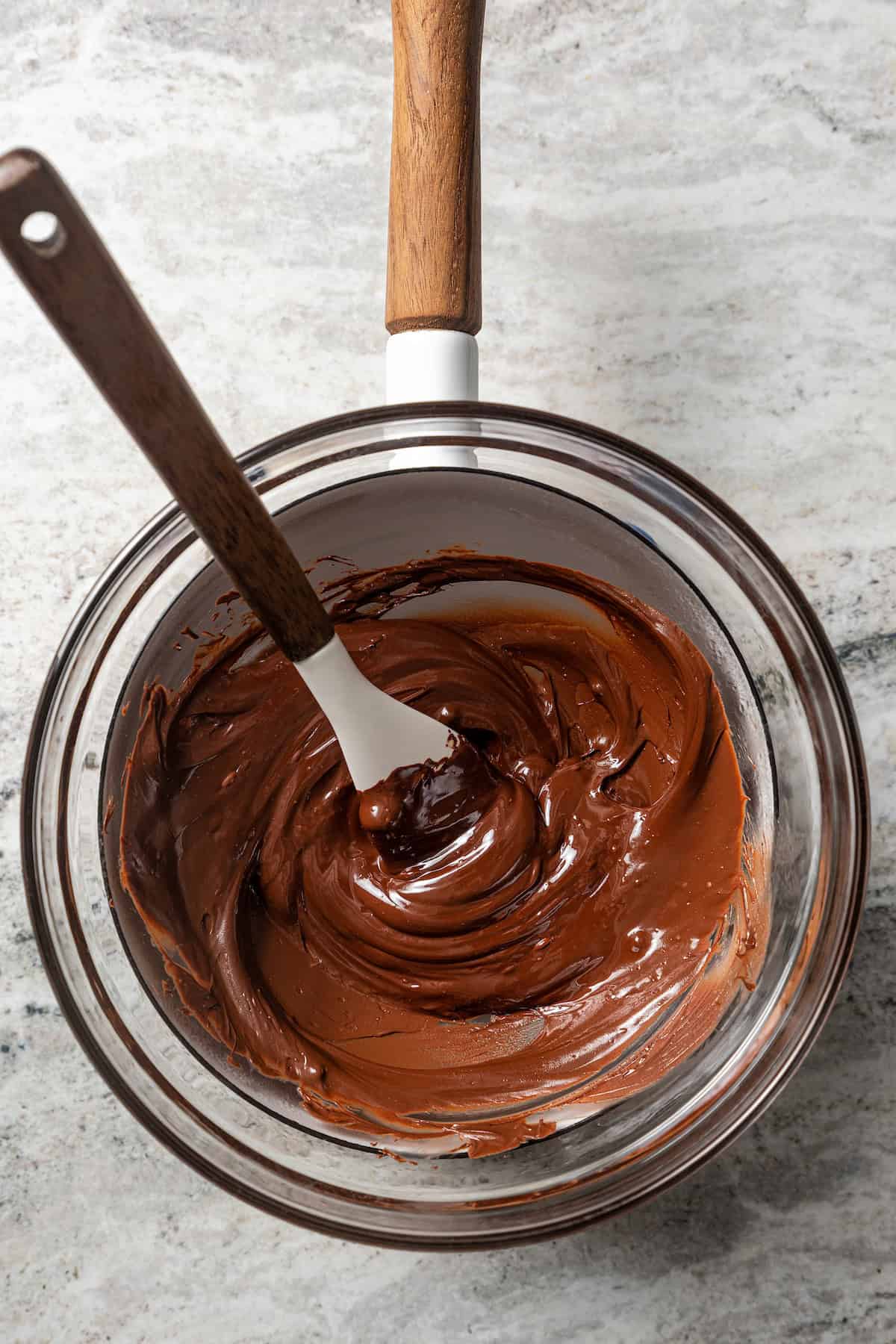 Melted chocolate in a double boiler with a spoon.