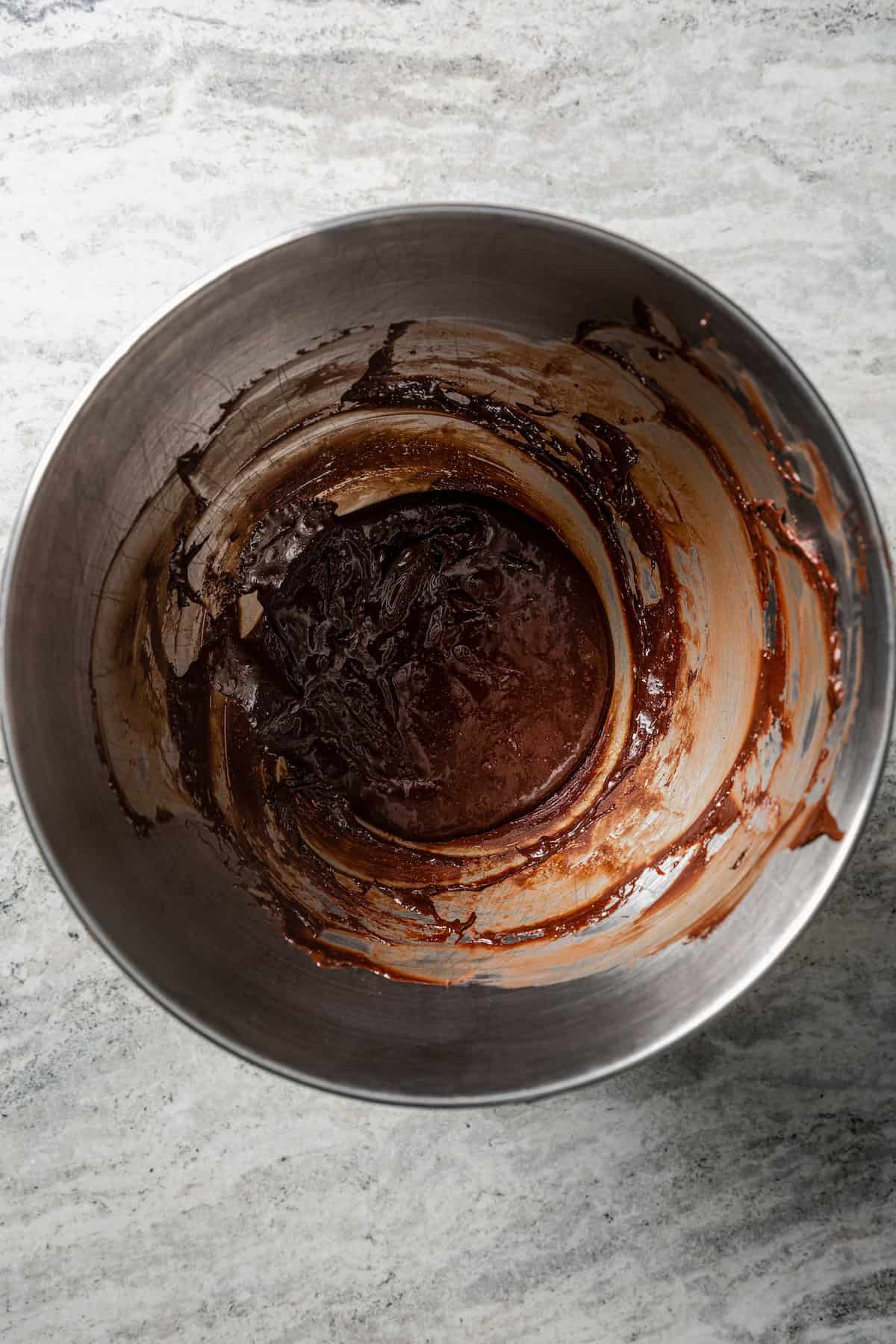 Melted chocolate combined with the egg yolk mixture in a metal bowl.