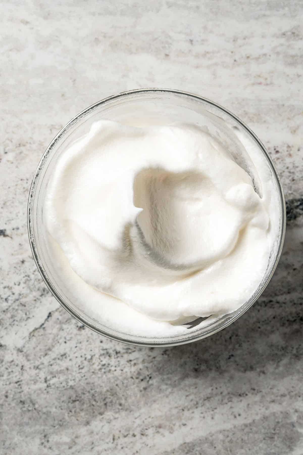 Whipped egg whites in a glass bowl.