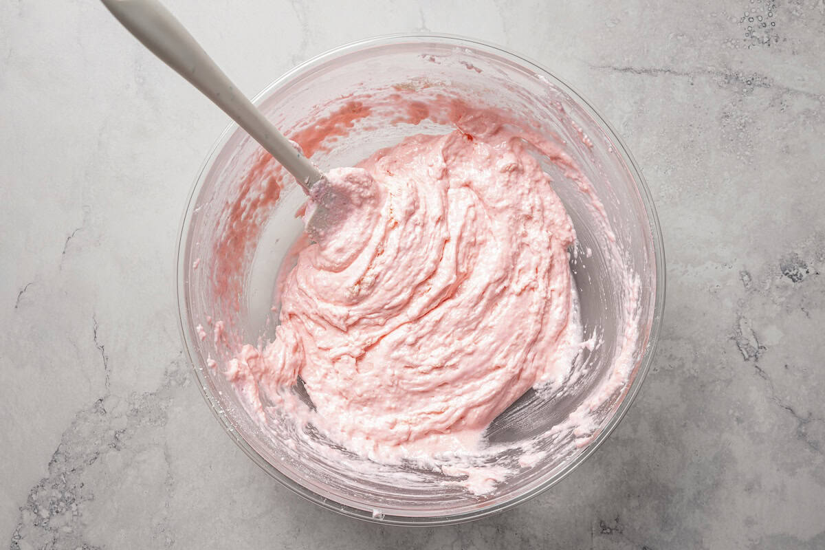 Pink meringue in a bowl with a spoon.