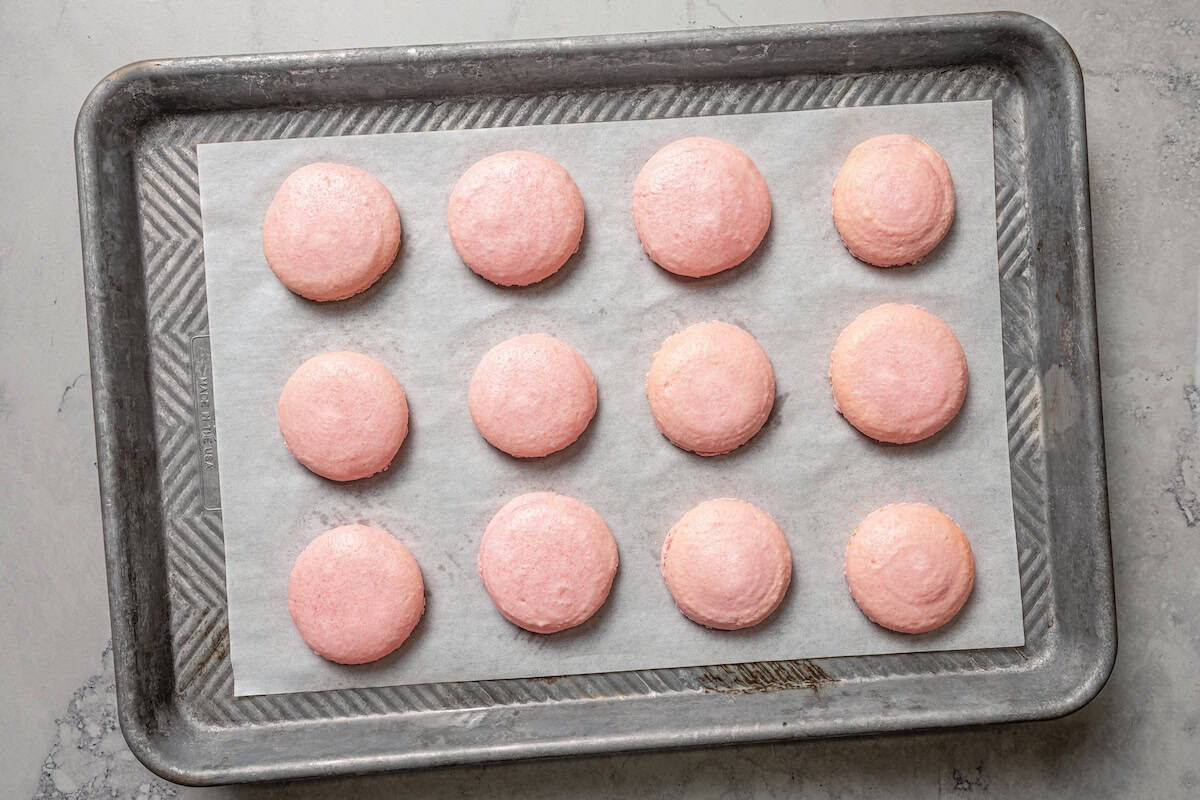 Baked macaron shells on a baking sheet.