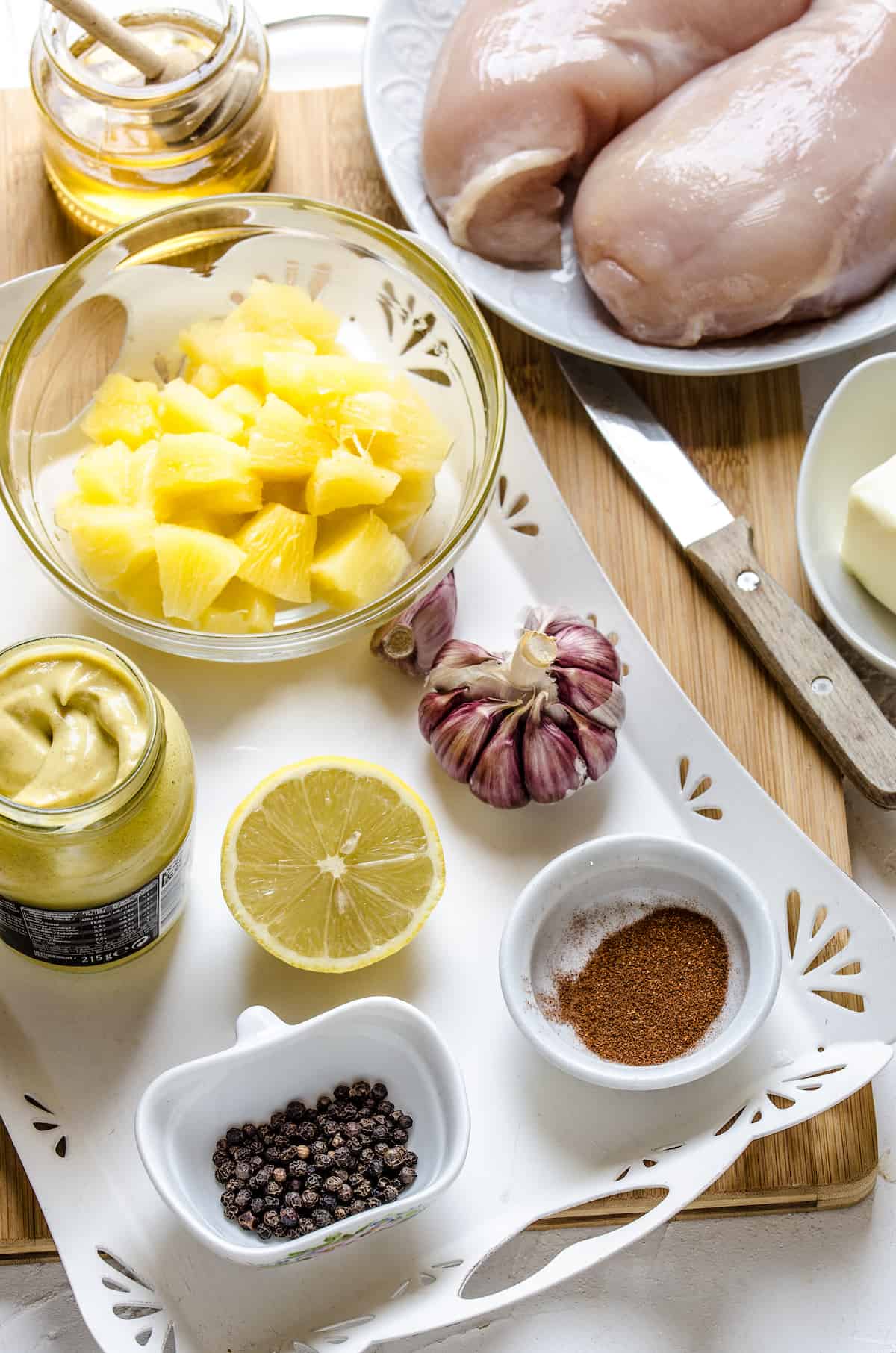The ingredients for Hawaiian baked chicken: Chicken breasts, butter, paprika, pepper, dijon mustard, pineapple chunks, honey and lemon.