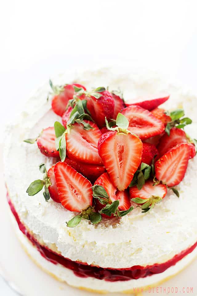 Overhead view of a strawberrry shortcake cake topped with whipped cream and fresh strawberries.