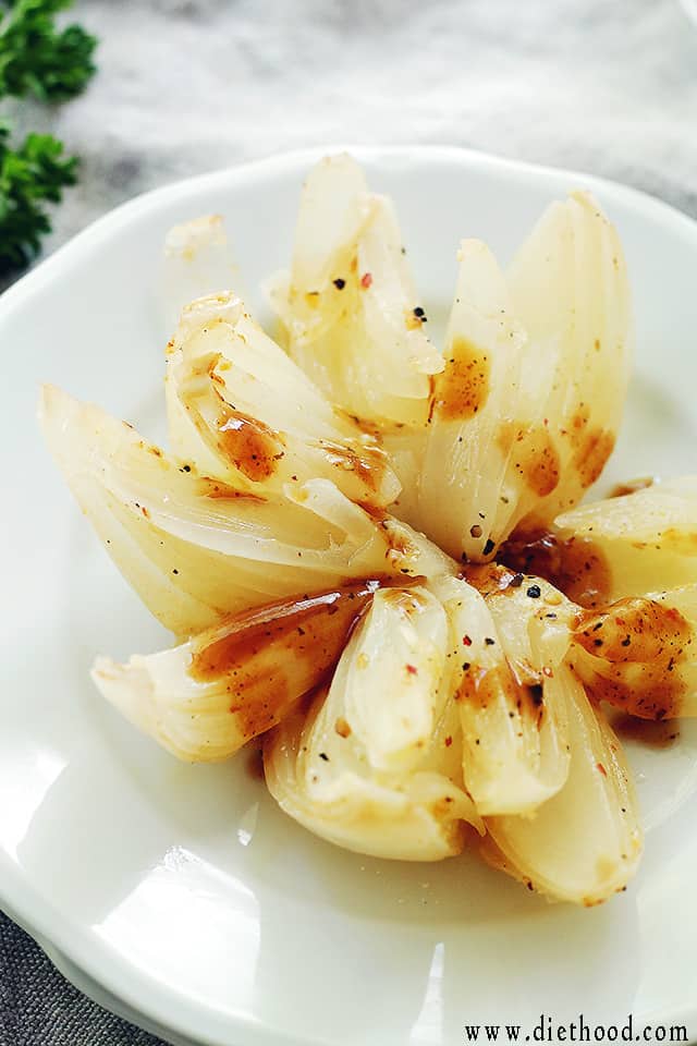 Grilled Blooming Onion served on a plate and drizzled with steakhouse sauce.