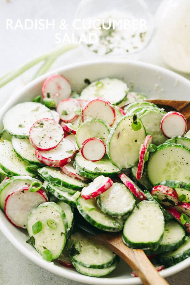 Tossing a Radish and Cucumber Salad in a white salad bowl.