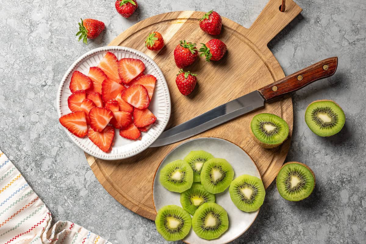 Overhead view of sliced strawberries and kiwis on plates.