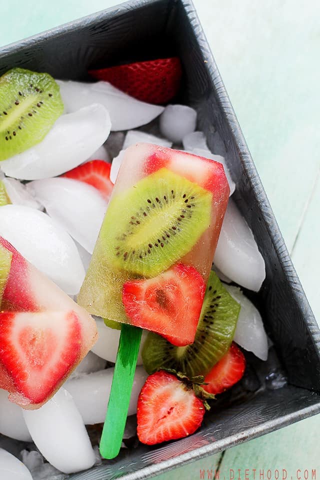 Strawberry and kiwi popsicles in a bowl with ice cubes