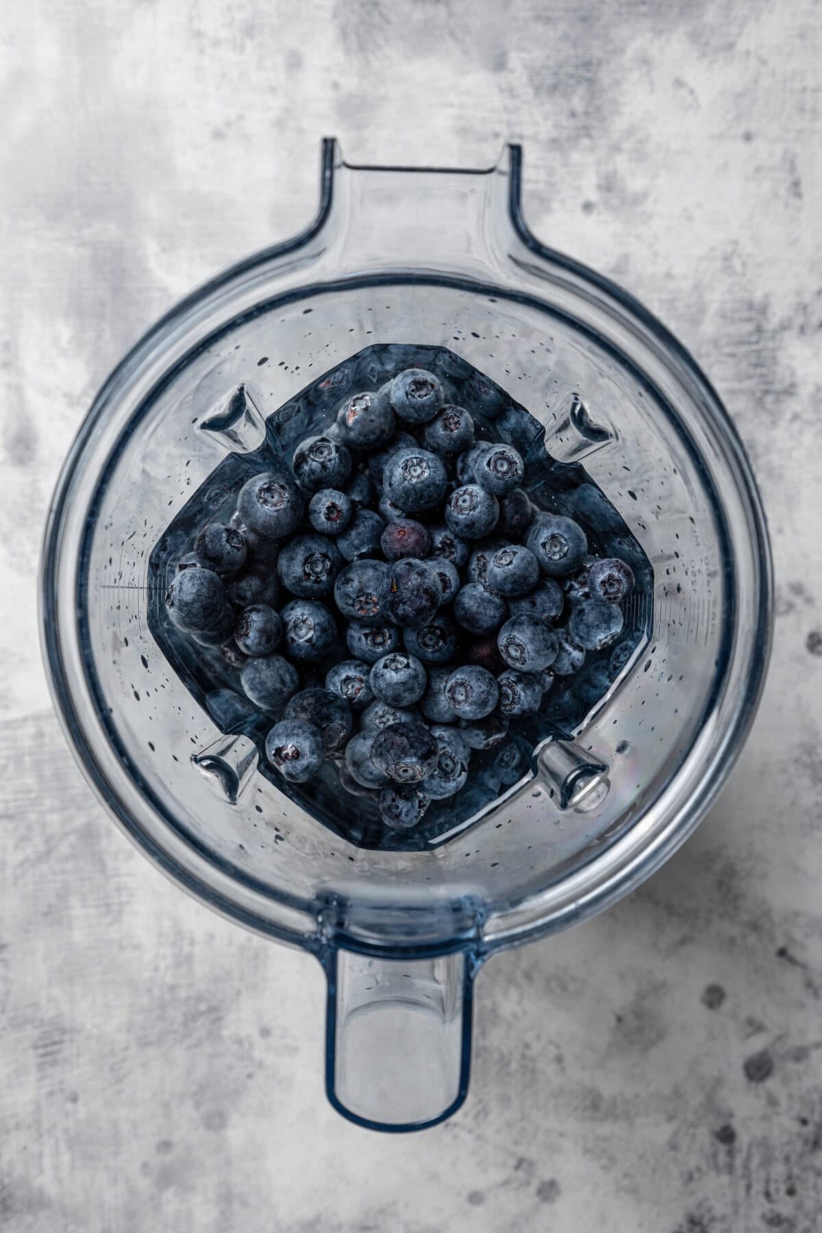 Blueberries and water added to a blender.