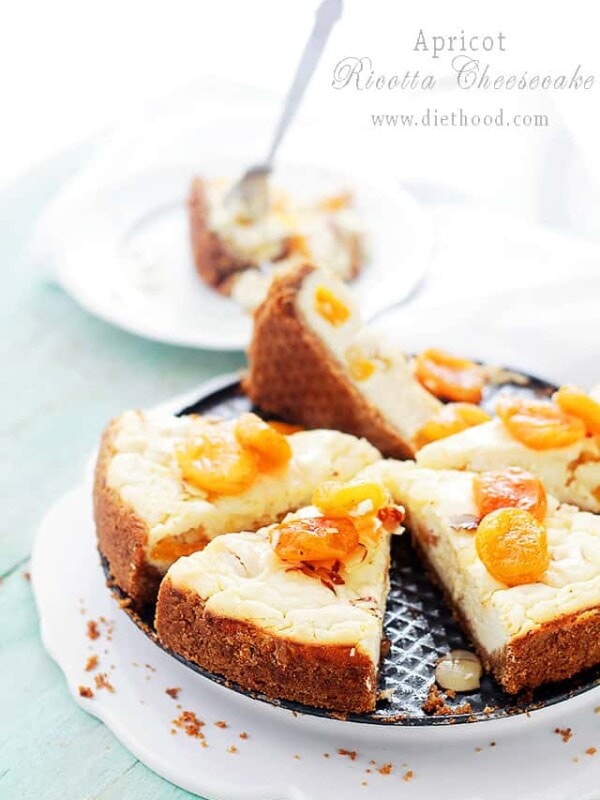 A sliced apricot-ricotta cheesecake with apricots and honey on top.