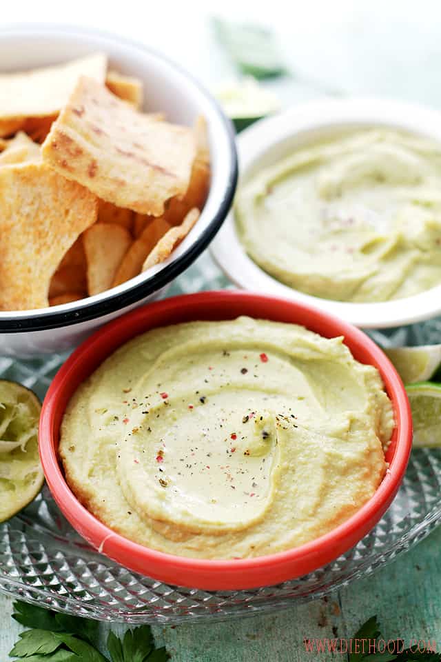 Avocado Hummus in a small red bowl next to a bowl of pita chips