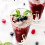 A colorful Agua Fresca drink in a tall glass with blueberries and mint