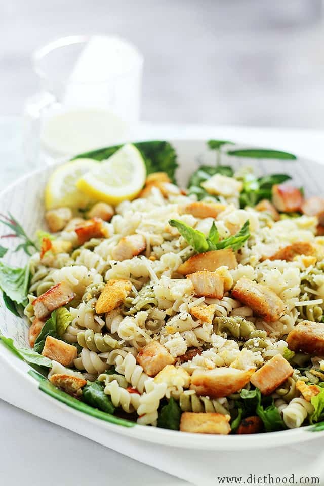 Weekly Menu Plan Chicken Caesar pasta salad in a bowl garnished with lemon wedges.