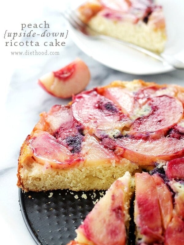 Peach upside down cake cut into slices, with a slice of cake on a plate in the background.