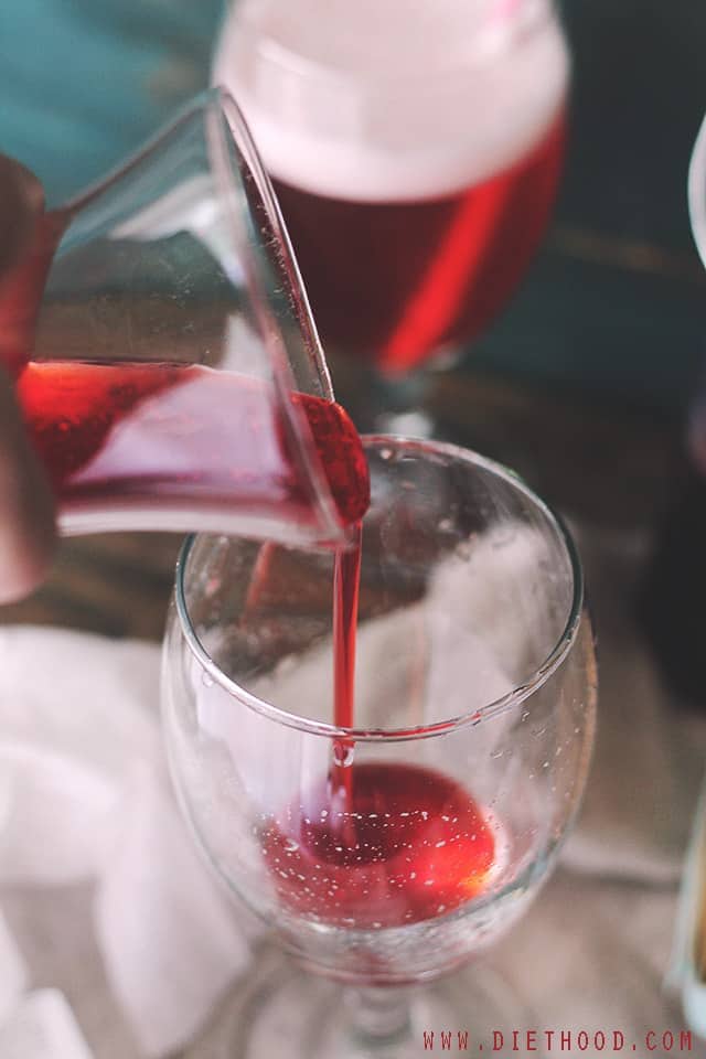 Pouring strawberry syrup into a glass.