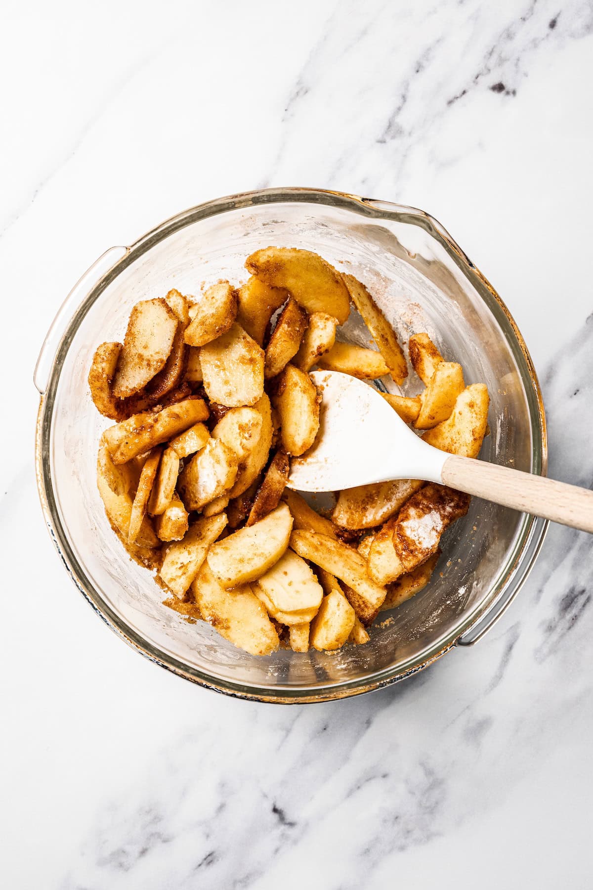 This apple pie cake has juicy caramel apples layered into a buttery crust, baked beneath a soft, sweet cake layer. It's easier than pie! Apples tossed with brown sugar and spices in a bowl.