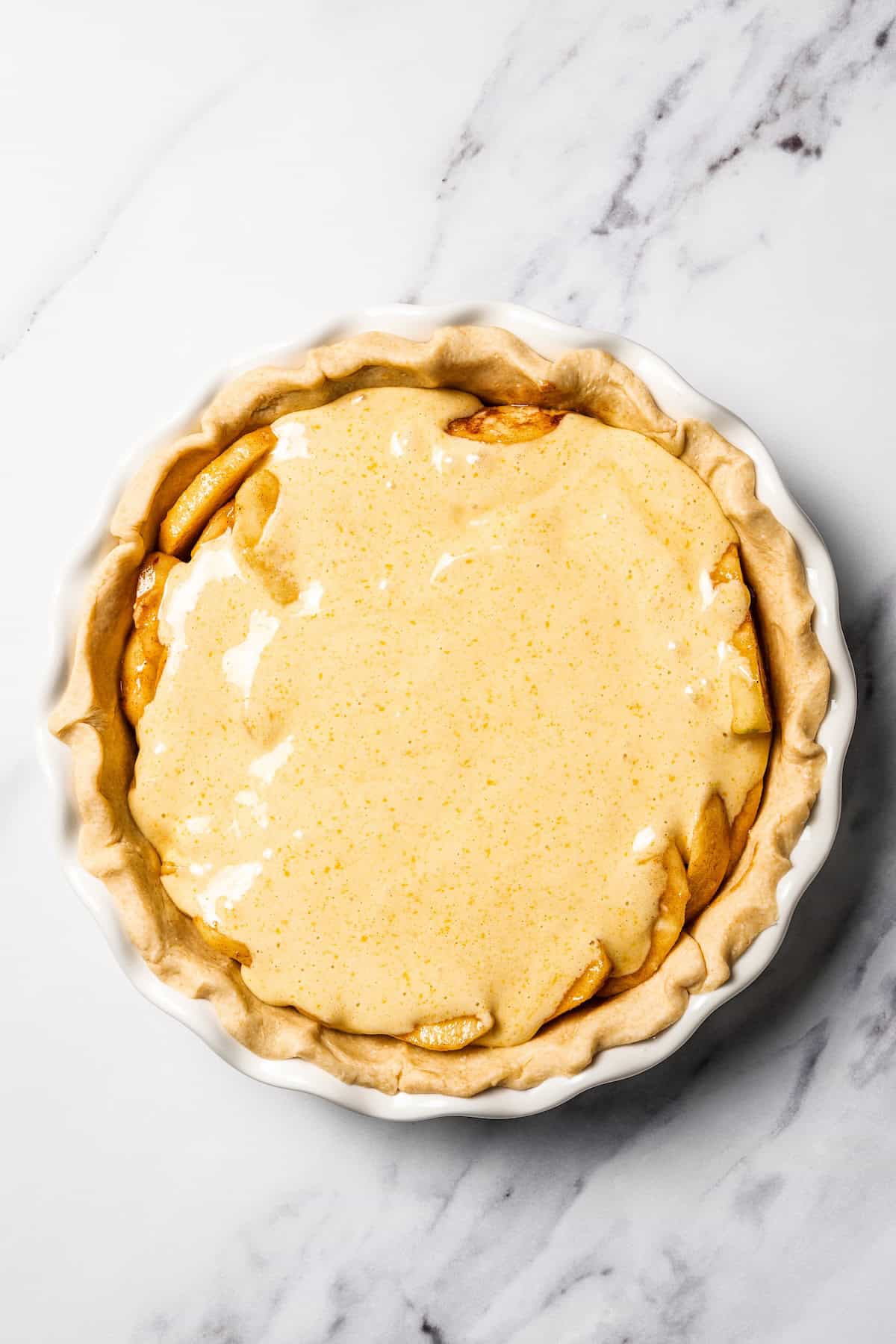 This apple pie cake has juicy caramel apples layered into a buttery crust, baked beneath a soft, sweet cake layer. It's easier than pie! Cake batter poured on top of the assembled apple pie cake.