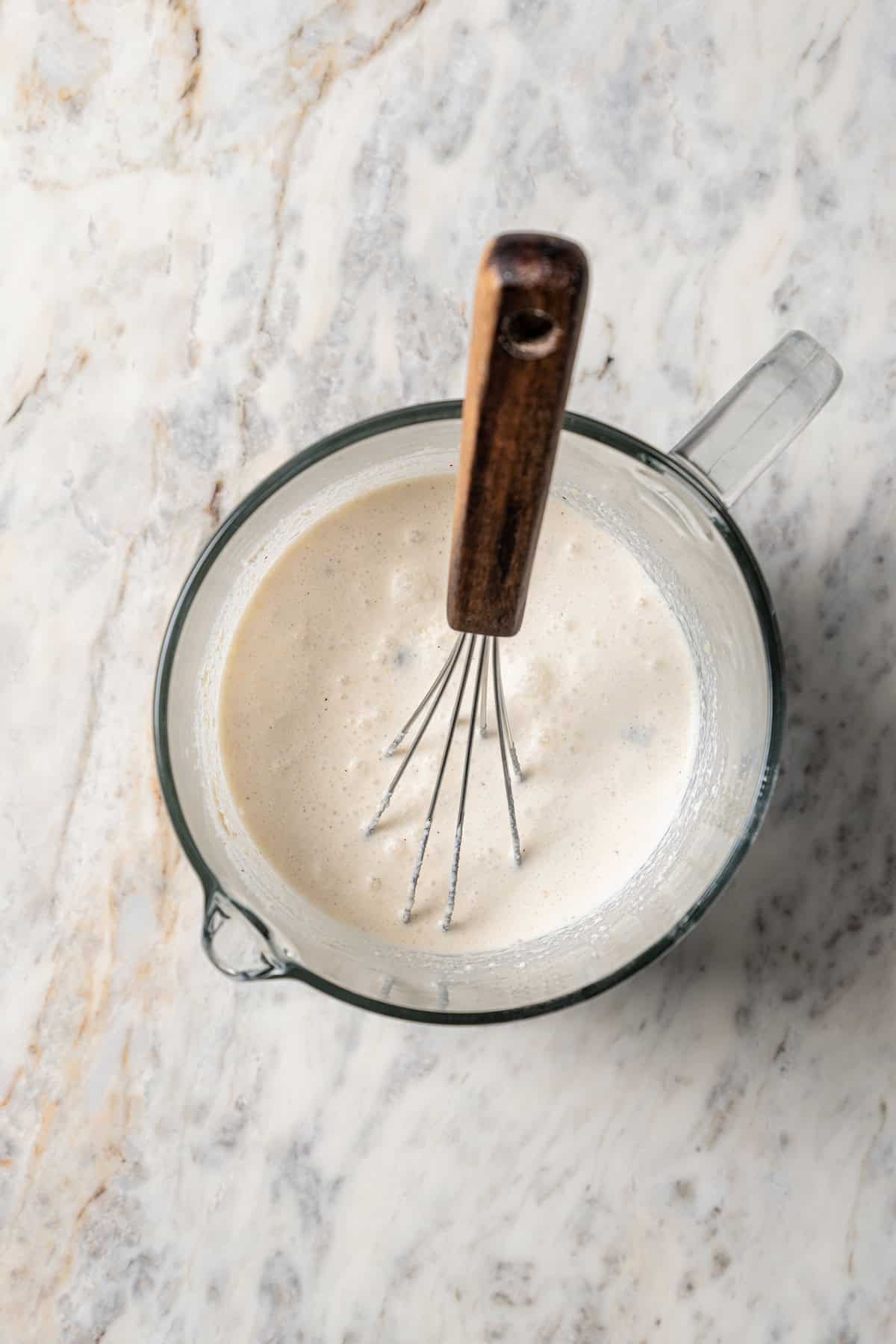 Creamy cheese sauce combined in a mixing bowl with a whisk.