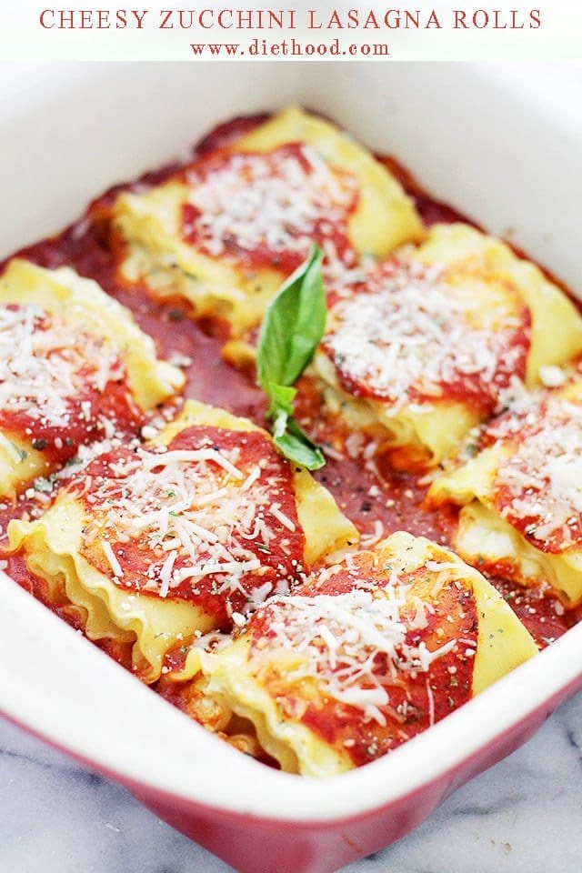 Cheesy Zucchini Lasagna Rolls arranged in a baking dish and topped with tomato sauce and cheese.