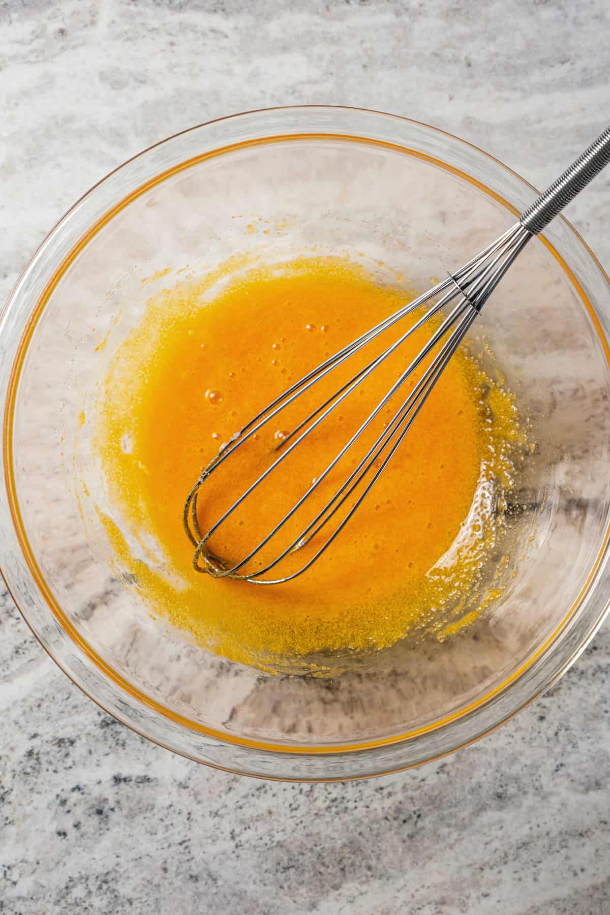 Sugar whisked with egg yolks in a bowl.