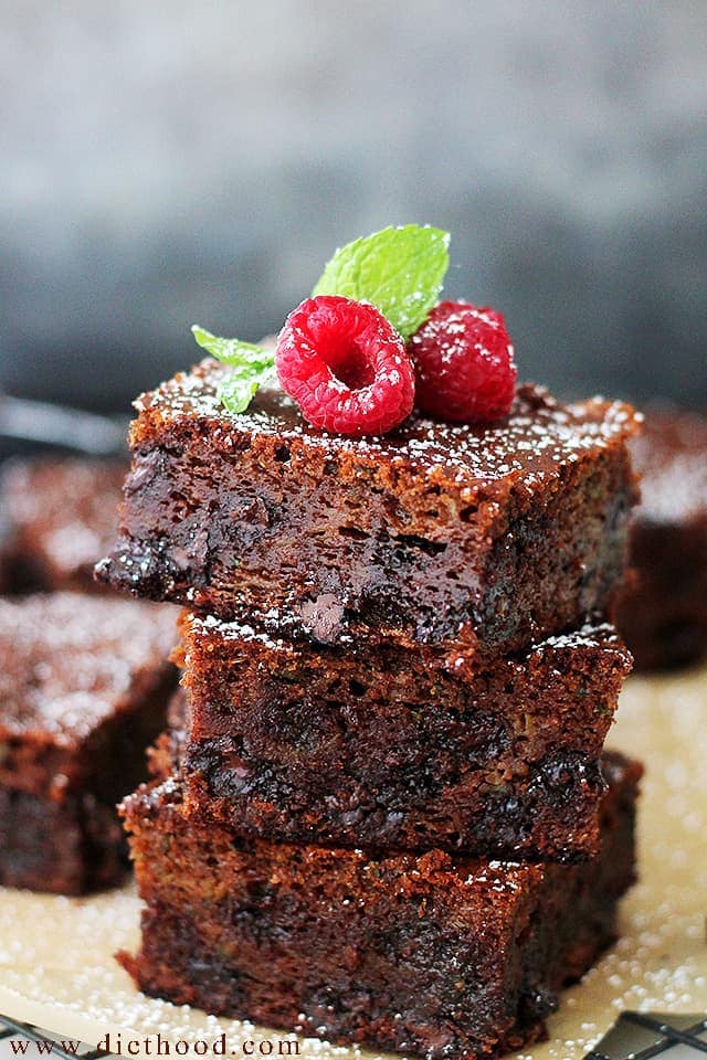 3 squares of Chocolate Zucchini Brownies stacked one on top of the other and topped with raspberries