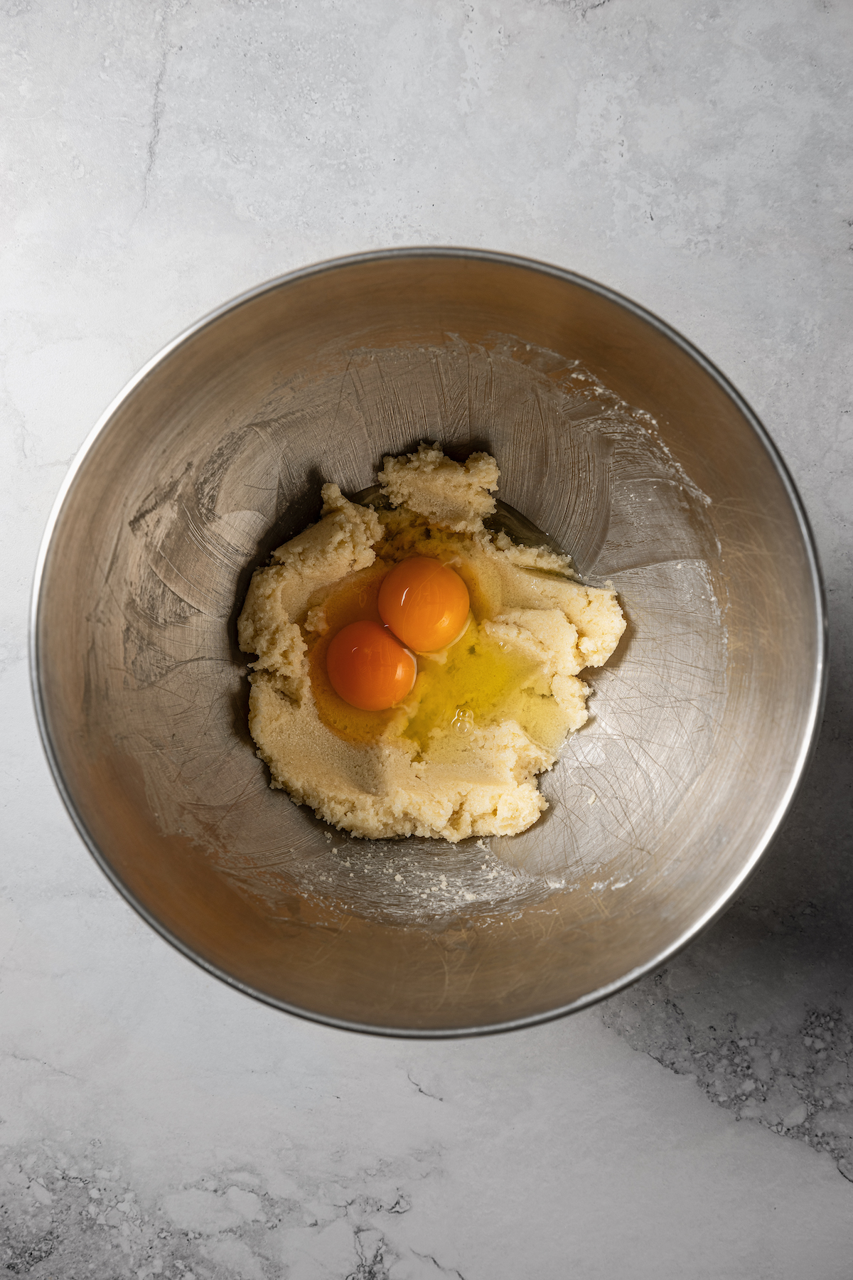 Eggs added to creamed butter and sugar in a bowl.