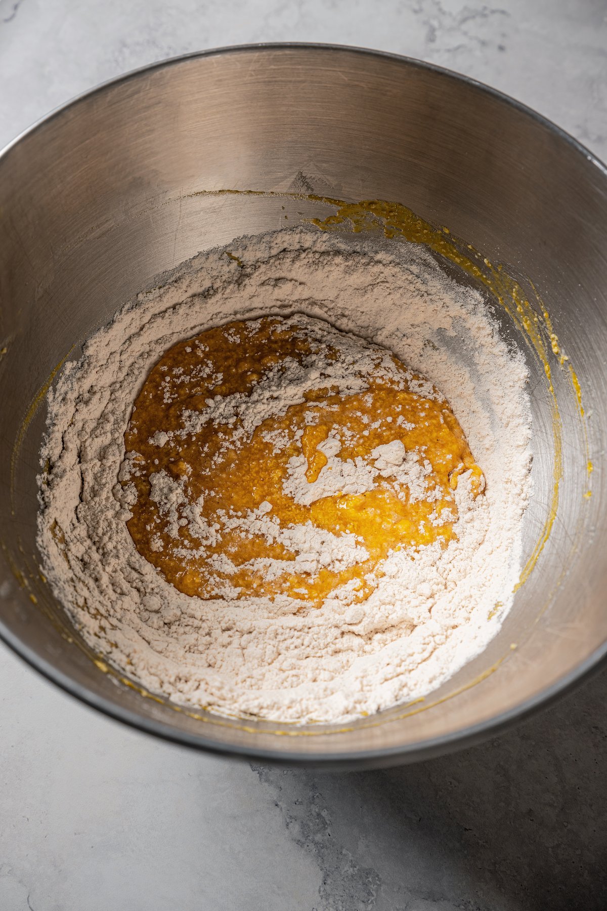 Wet ingredients added to dry ingredients in a mixing bowl.