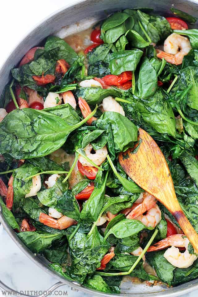This lemon shrimp spaghetti is an easy 30-minute dinner with juicy shrimp, tomatoes, spinach, garlic, and plenty of fresh lemon flavor. Close up of cooked shrimp, spinach leaves, and cherry tomatoes.